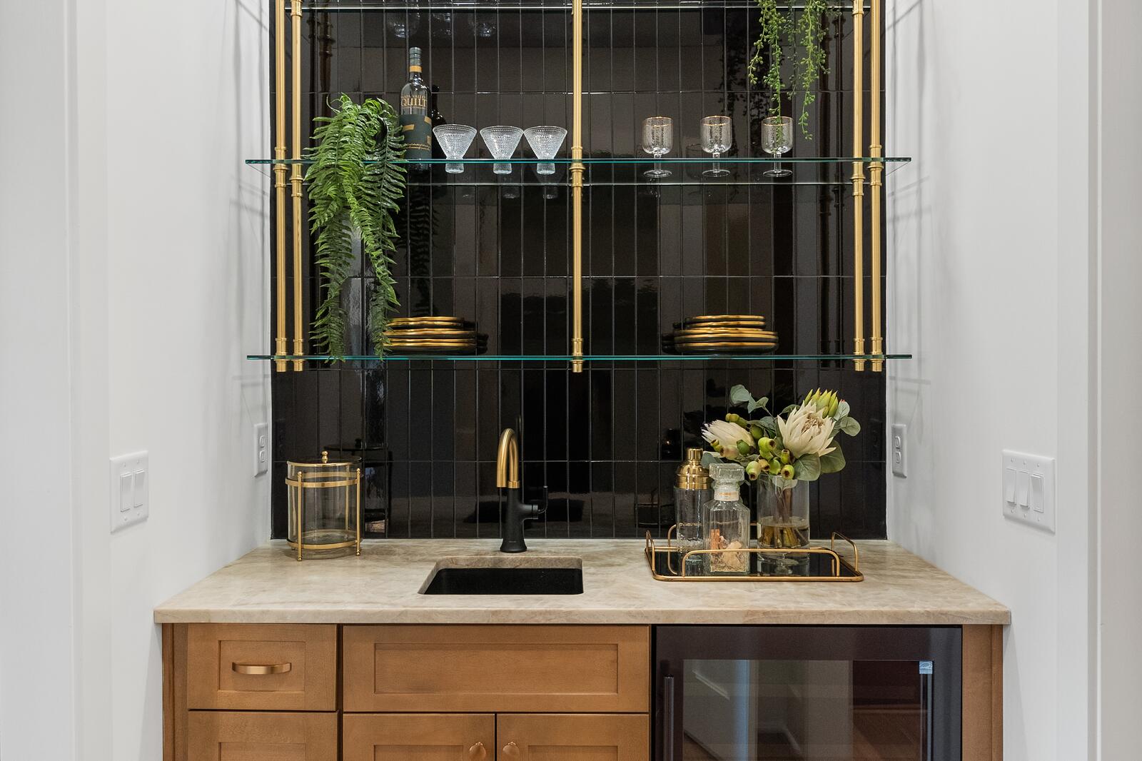 A finished lower-level wet bar with oak cabinetry and glass-fronted display shelving